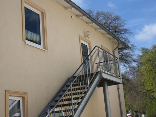 En beige bygning med balkon og trappe.