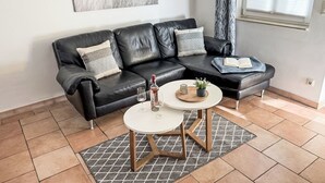 A modern living room with a black leather sofa, a white coffee table, and a view of the sea through a window. - Apartment Meise by Interhome (Zinnowitz)