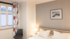 A hotel room with a bed, a chair, a bedside table with a lamp, and a window with blinds. - Apartment Meise by Interhome (Zinnowitz)