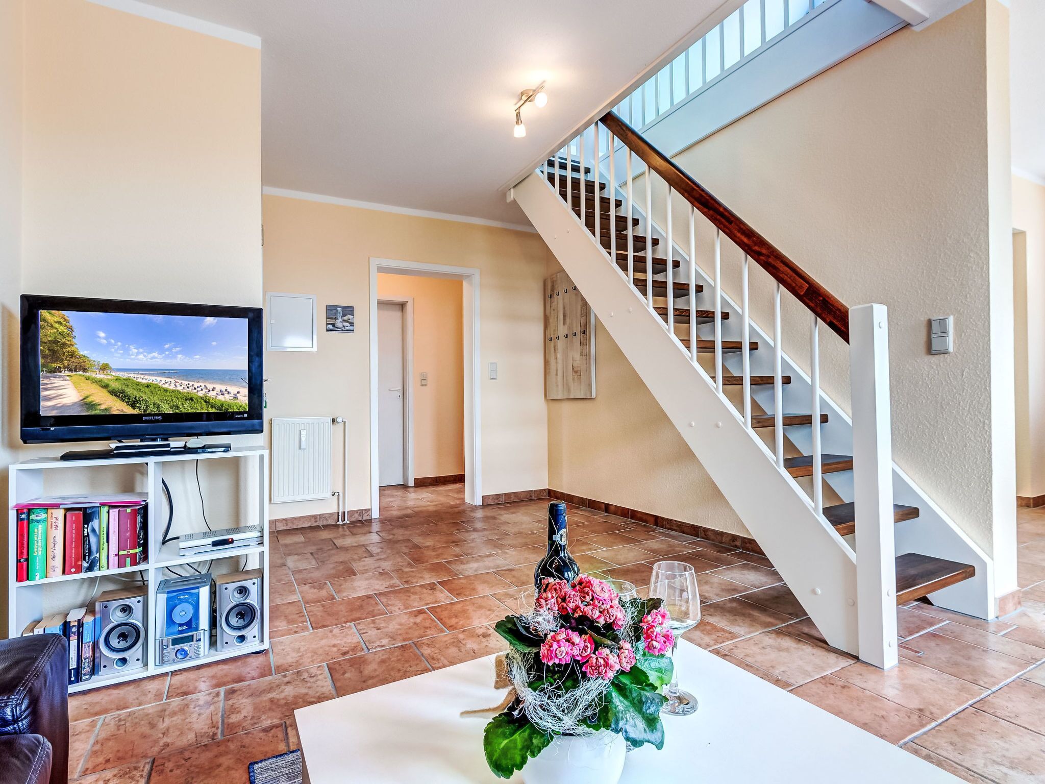 Un salon avec une télévision, une bibliothèque et un escalier.
