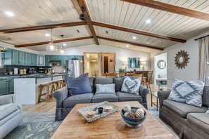 A spacious living area with a wooden ceiling, a kitchen with teal cabinets, and a dining area with a chandelier. - 'Sweetwater Bluff' Home On The Hiawassee w/ Views! (Hayesville)
