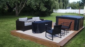 A patio area with a sofa set, a covered table, and a hot tub. - Charming 2 BR home  - newly renovated  (Potsdam)
