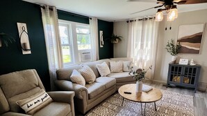 A cozy living room with a sectional sofa, a beige armchair, a patterned rug, and a ceiling fan. - Charming 2 BR home  - newly renovated  (Potsdam)