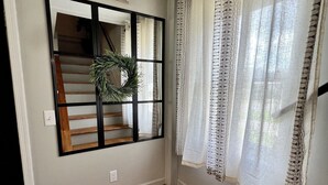 A room with a wooden floor, a window with a wreath decoration, and patterned curtains. - Charming 2 BR home  - newly renovated  (Potsdam)