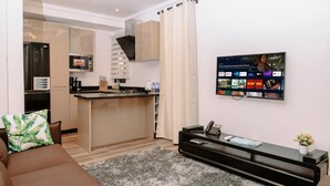A modern living room with a sofa, a coffee table, and a flat-screen TV mounted on the wall displaying a streaming service interface. - Reddington Beach Resort (Anloga)
