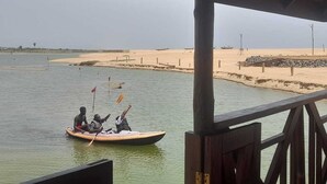 A wooden pier with a sandy beach and calm water in the background. - Reddington Beach Resort (Anloga)