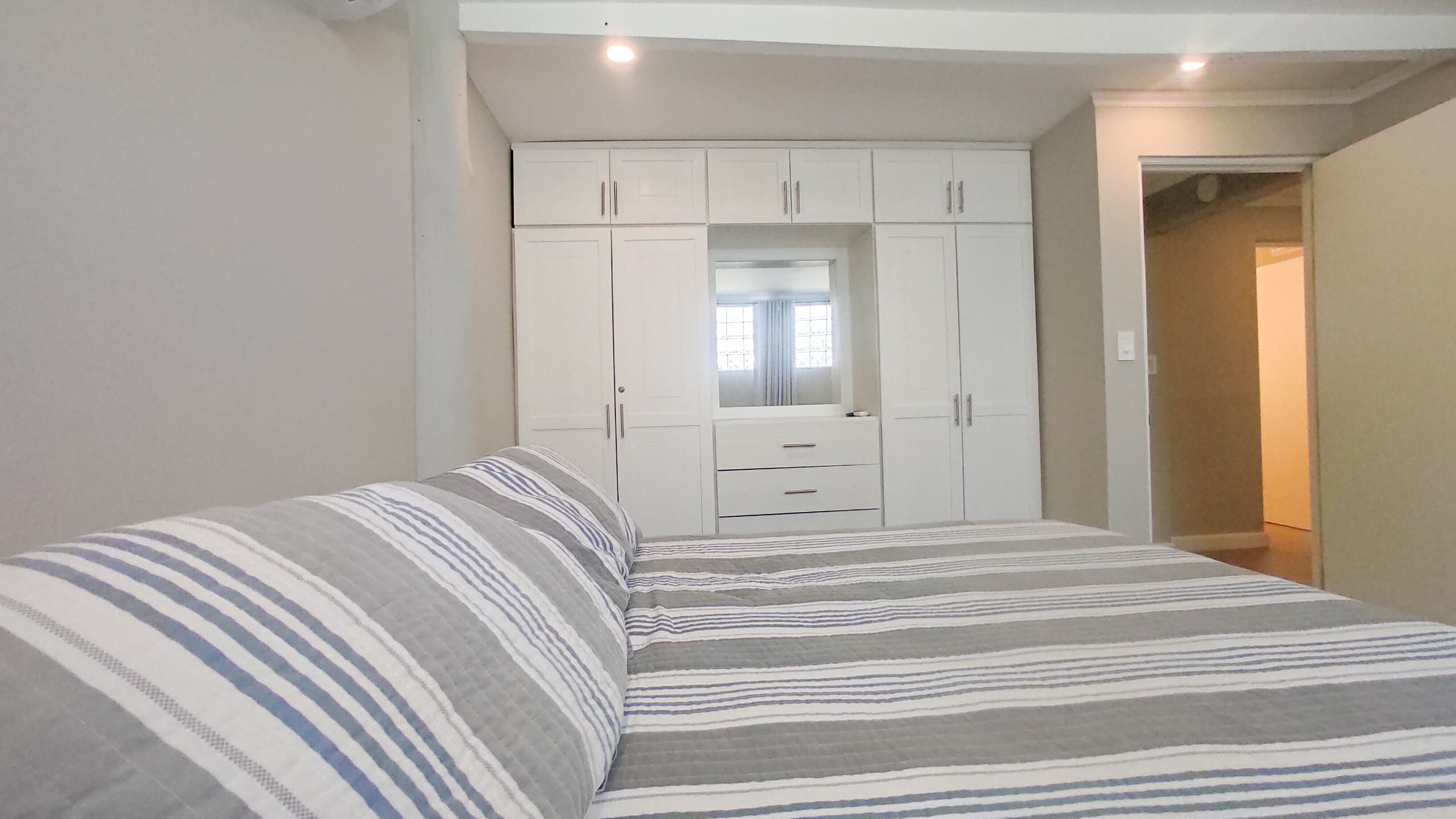 A bedroom with a bed, a wardrobe, and a mirror.