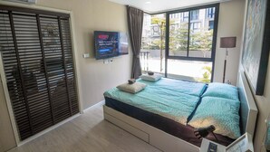 Un dormitorio con cama, televisión, ventana y puerta corredera.