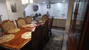 Un coin repas avec une table et des chaises en bois, un tapis à motifs et une cuisine en arrière-plan.