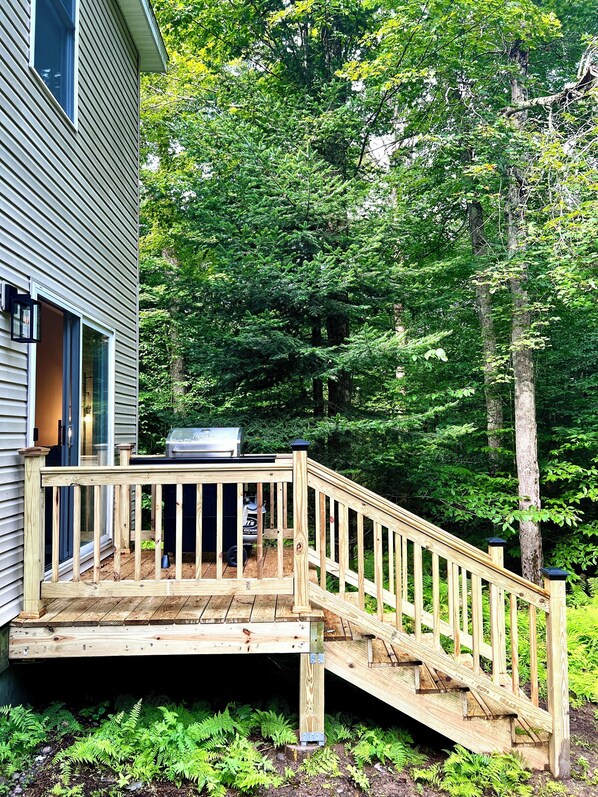 A wooden deck with a staircase leading to a house.