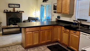 A modern kitchen with wooden cabinets, a black countertop, and a built-in dishwasher. - Peaceful Family Retreat – Spacious 4BR Home - 5 acres of forest (Inlet)