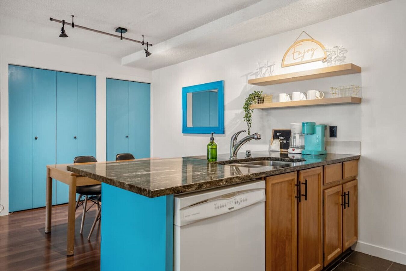 A modern kitchen with a central island, blue doors, and a coffee station.