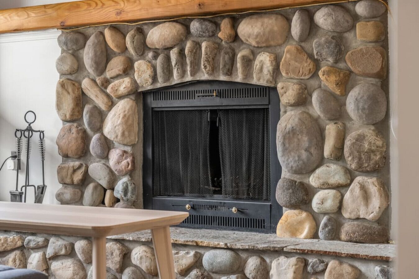 A stone fireplace with a black metal door, surrounded by irregularly shaped stones.