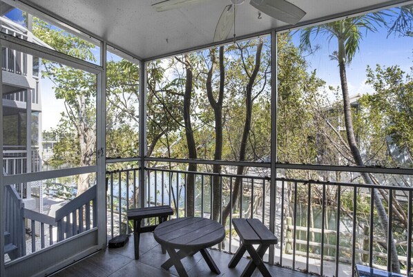 A covered outdoor area with a table and benches, overlooking a body of water and trees.