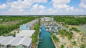 A marina with boats docked, a hotel with a pool, and a beach with palm trees. - Kawama 3 bedroom townhouse--2 heated pools, marina, tennis, lagoon & much more! (Key Largo)