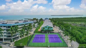 A tennis court with a building in the background. - Kawama 3 bedroom townhouse--2 heated pools, marina, tennis, lagoon & much more! (Key Largo)