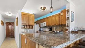 A kitchen with wooden cabinets, granite countertops, and pendant lighting.