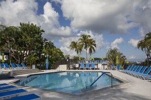 A pool area with blue lounge chairs and palm trees. - Gorgeous Moon Bay Condo Heated Pool Beach (Key Largo)