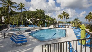 A pool area with multiple swimming pools, lounge chairs, and palm trees.
