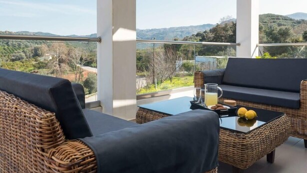 A balcony with wicker furniture, a glass table, and a view of the countryside. - Alyona Villa | Private Pool, Garden & Playground (Skines)