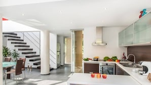 Una cocina moderna con comedor, que incluye una escalera, una mesa de comedor con sillas y una encimera con electrodomésticos.