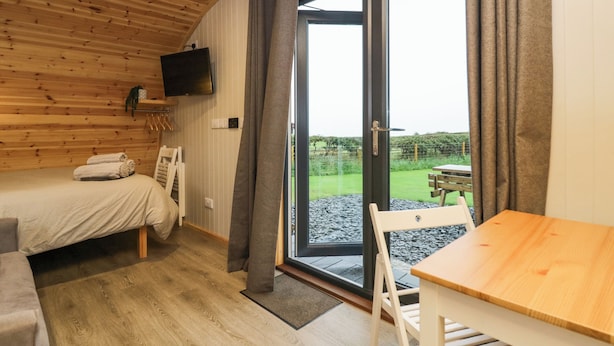 Una habitación acogedora con una cama, una mesa y un televisor montado en la pared.