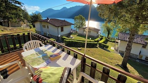 A terrace with a table and chairs, overlooking a lake and houses with manicured gardens. - Close to the lake with panoramic views (Tre Capitelli)