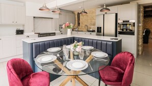 Una cocina moderna con armarios blancos, una isla central con asientos y electrodomésticos de acero inoxidable.