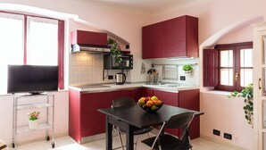 A compact kitchen with red cabinets, a black dining table, and a fruit bowl. - notaMI - Forcella Fashion District  (Milan)
