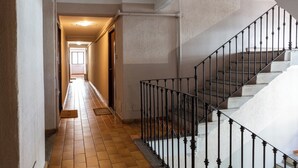 A hallway with a tiled floor leading to a staircase with a metal railing. - notaMI - Forcella Fashion District  (Milan)