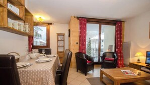 A dining area with a table set for four, a coffee table, and two chairs. - Flat with parking and balcony in Centre (Chamonix-Mont-Blanc)