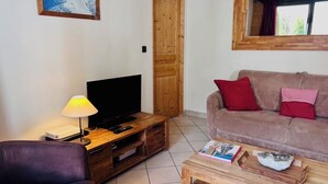 A living room with a television, wooden coffee table, and a couch with red cushions. - Flat with parking and balcony in Centre (Chamonix-Mont-Blanc)