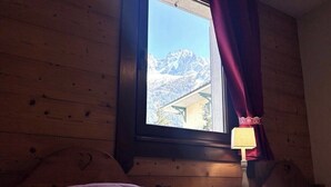 A wooden cabin room with a window, a bedside table, and a lamp. - Flat with parking and balcony in Centre (Chamonix-Mont-Blanc)