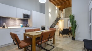 Eine moderne Küche mit weißen Schränken, einem Holztisch und einer Treppe zu einer oberen Ebene.