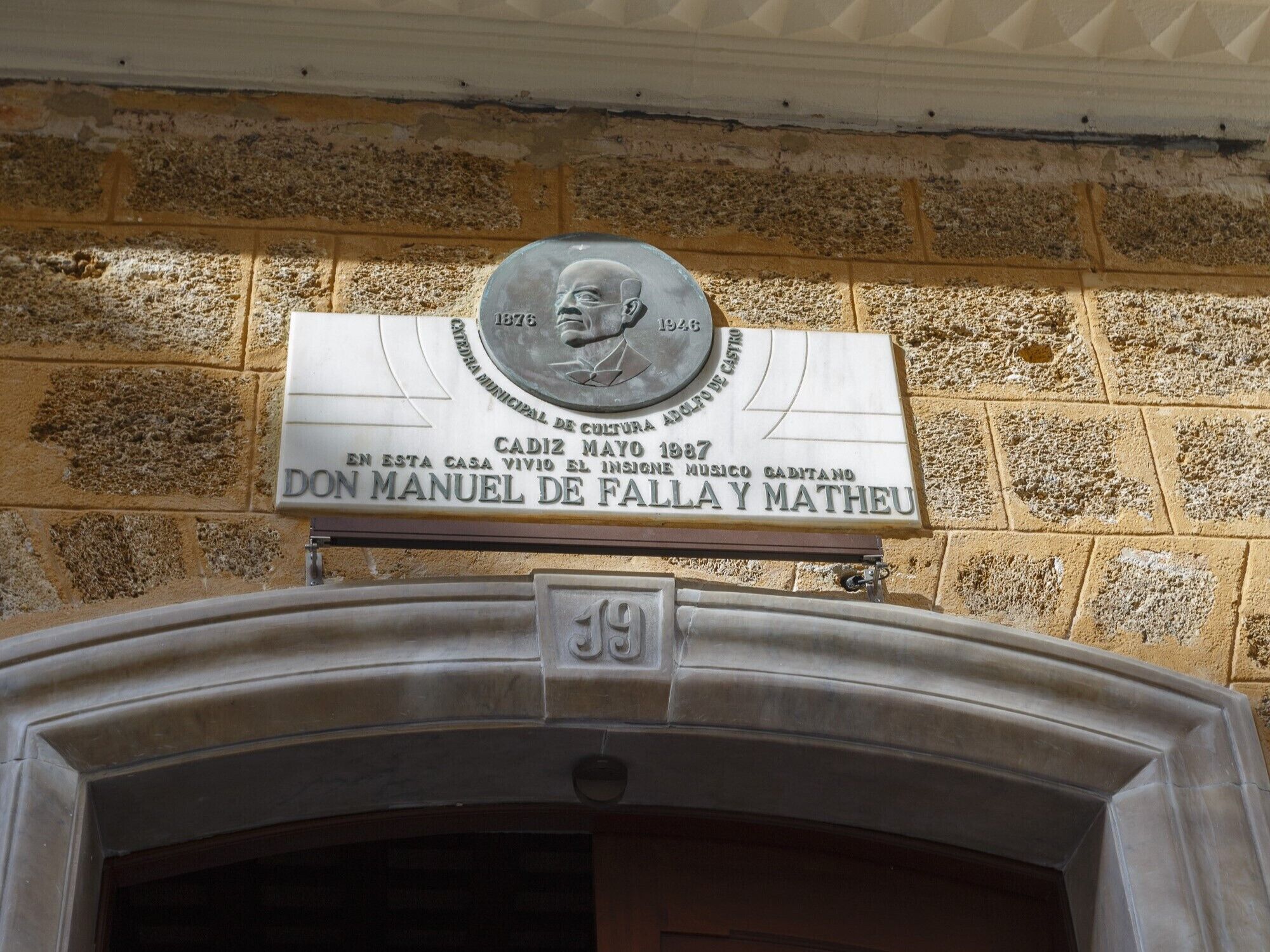 A plaque commemorating Don Manuel de Falla y Matheu, a musician, on a stone wall with a brick pattern.