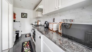 A modern kitchen with white cabinetry, a marble countertop, and a built-in oven. - Central London Apt - Sleeps 3 - Street Parking (London)