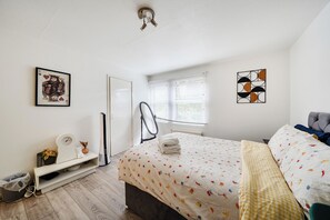 A bedroom with a bed, a desk, a chair, a radiator, a window with blinds, and a ceiling light fixture. - Central London Apt - Sleeps 3 - Street Parking (London)