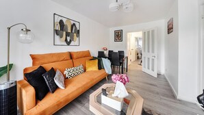 A modern living room with a sofa, a coffee table, and a painting on the wall. - Central London Apt - Sleeps 3 - Street Parking (London)