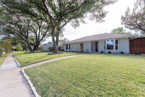 A single-story house with a well-maintained lawn and a sidewalk leading to the front door.