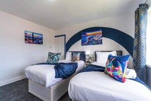 Een hotelkamer met twee bedden, een groot rondboogvenster en kunstwerken aan de wanden.