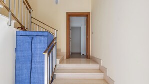 A staircase with a wooden door at the top, leading to a room with white walls and a tiled floor.