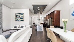 Cozinha moderna com armários de madeira escura, bancada branca e geladeira de aço inoxidável.
