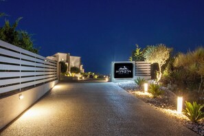 A nighttime entrance to a property named 'Horizon' with a paved pathway, illuminated sign, and landscaped surroundings.