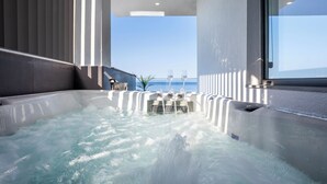 A hot tub with a view of the ocean, a window, and a modern interior design.