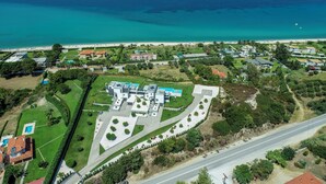 An aerial view of a coastal property with a large building complex, a road, and a beach.