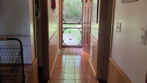 Un pasillo con piso de madera, una puerta con ventana y un cartel en la pared.