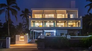 A modern two-story building with large windows and a well-lit entrance. - Raj Sea Front Beach Resort 102 (Mangaluru)