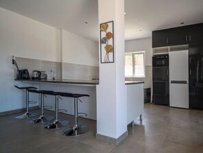Una cocina moderna con una isla central, taburetes de bar y un refrigerador grande.