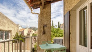 Un balcón con una mesa y sillas, vistas de los edificios circundantes y una estructura de pérgola.