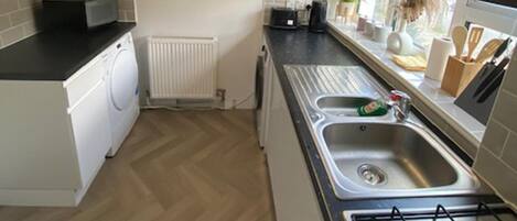 A kitchen with a stove, sink, and a microwave.
